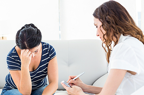 Therapist listening her patient and taking notes on white background