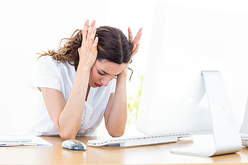 Upset businesswoman sitting at her desk on white background