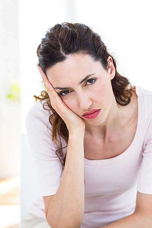 Upset brunette sitting on the couch on white background