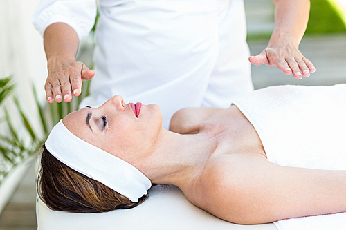 Calm woman receiving reiki treatment in the health spa