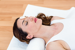 Relaxed brunette lying on mat with stones on wooden floor