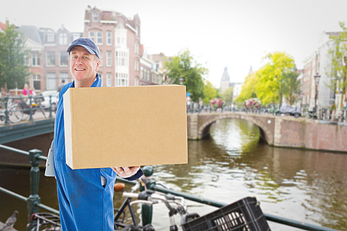 Composite image of happy delivery man showing cardboard box