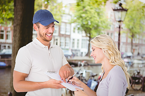 Composite image of happy delivery man getting signature from customer