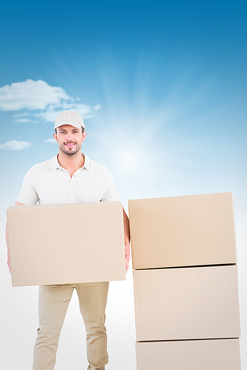 Composite image of confident delivery man holding cardboard box