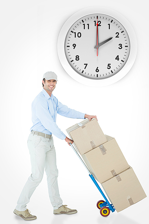 Composite image of happy delivery man pushing trolley of cardboard boxes