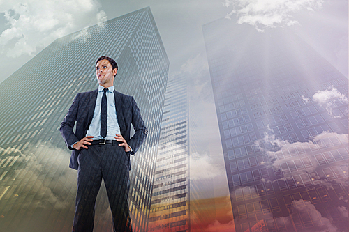 Composite image of serious businessman with hands on hips