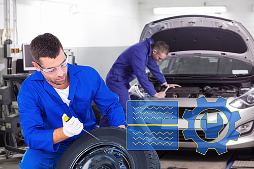 Composite image of mechanic working on tire over white background