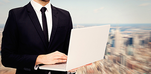 Composite image of mid section of a businessman using laptop