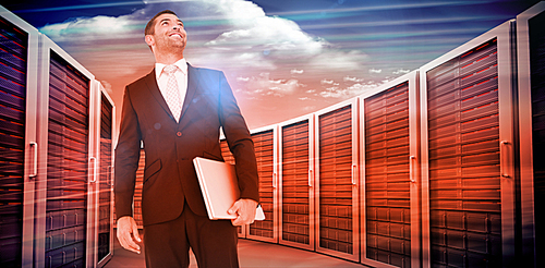 Composite image of businessman looking up holding laptop