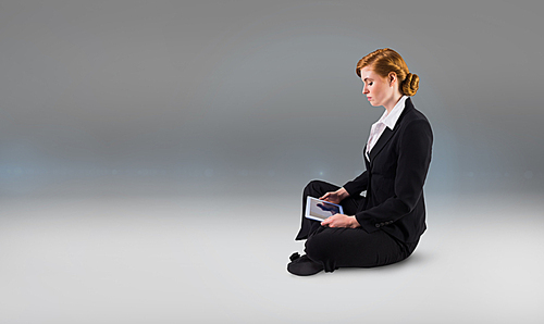 Composite image of redhead businesswoman using her tablet pc