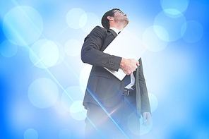 Composite image of businessman looking up holding laptop