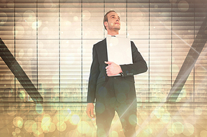 Composite image of businessman looking up holding laptop