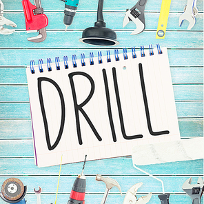 Drill against tools and notepad on wooden background