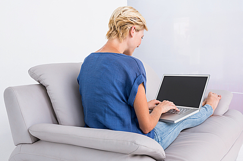 Blonde woman using her laptop on the couch