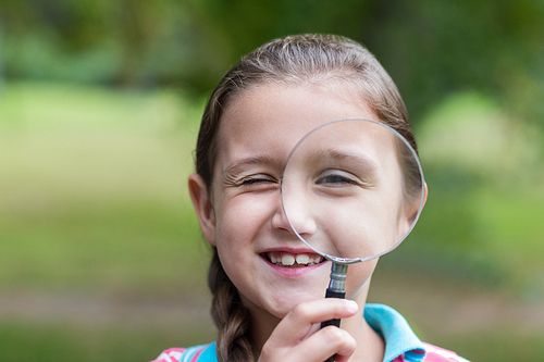 Curious little girl looking through magnifying glass