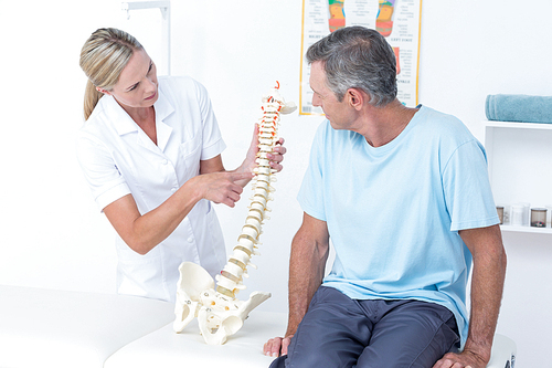 Doctor showing her patient a spine model in medical office