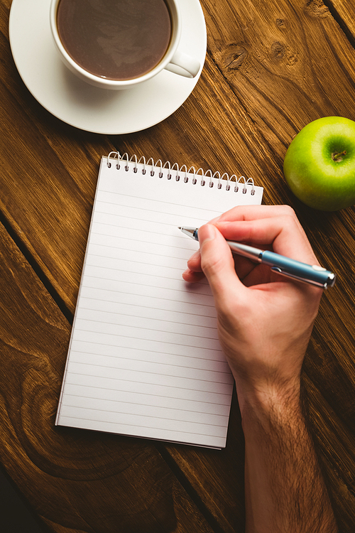 Hand writing on the notepad on a desk