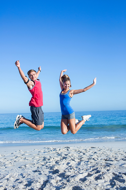 Happy couple jumping together at the beach