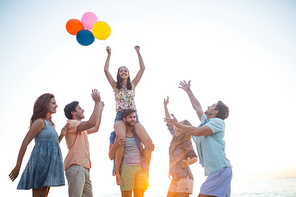 Happy friends dancing on the sand with balloon at the beach