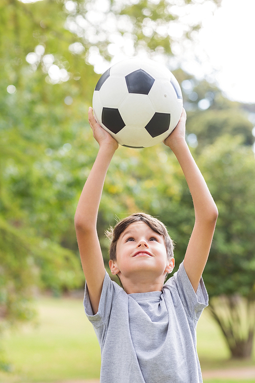 Boy holding a soccer ball in the park on a sunny day