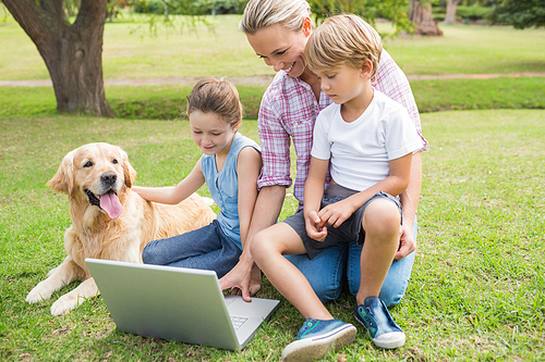 Happy family with their dog using laptop on a sunny day