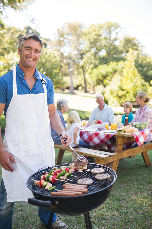 Happy man doing barbecue for his family in a sunny day