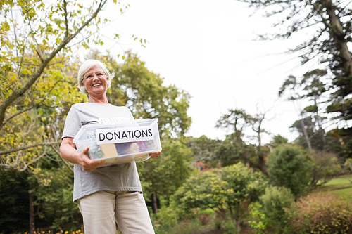 Happy grandmother holding donation box on a sunny day