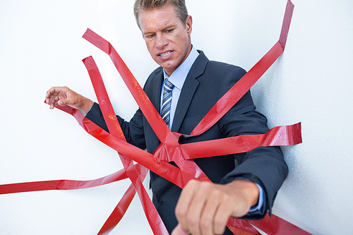 Businessman trapped by red tape on white background