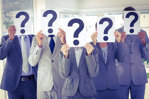 Business team holding question marks over face in the office