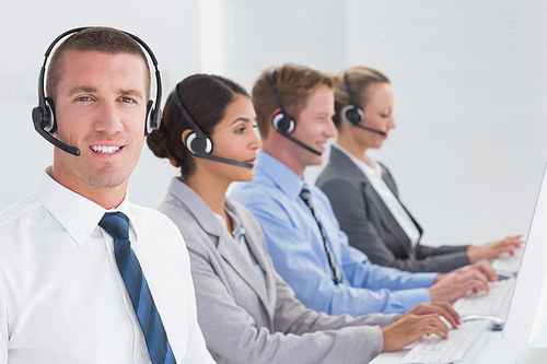 Business team working on computers and wearing headsets in call center