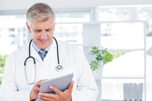 Smiling doctor holding tablet in medical office