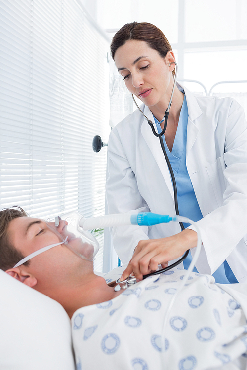 Doctor auscultating her patients chest in hospital room