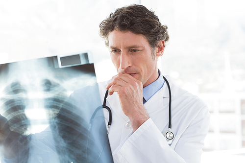 Serious doctor looking at X-ray in medical office