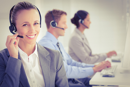 Business team working on computers and wearing headsets in call center