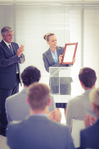 Pretty businesswoman receiving prize in meeting room