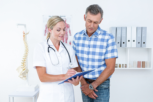 Doctor showing clipboard to her patient in medical office