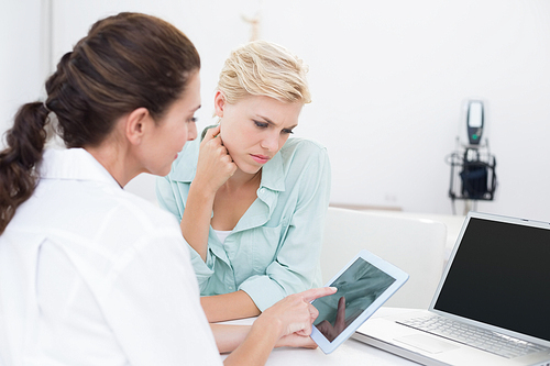 Doctor using tablet pc with her patient in medical office