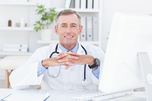 Smiling doctor  with hands crossed in medical office