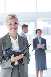 Smiling businesswoman holding files and  in the office