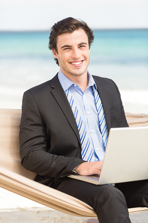 Businessman using laptop on the hammock at the beach