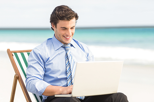 Businessman using his laptop at the beach