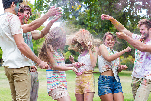 Happy friends throwing powder paint on a sunny day