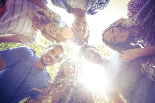 Happy friends huddling in circle in the park on a sunny day