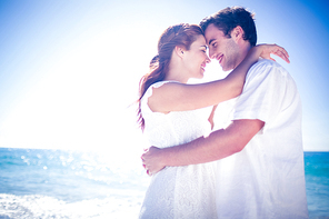 Happy couple hugging at the beach on a sunny day