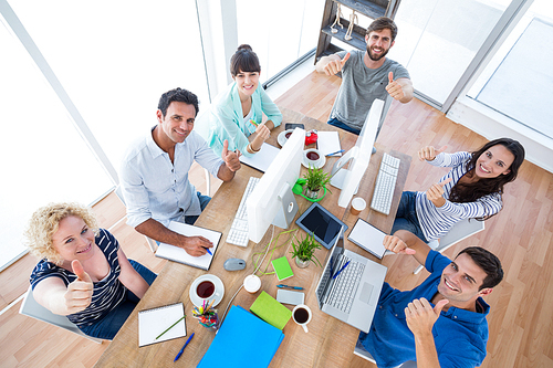 Creative business team gesturing thumbs up in a meeting at office