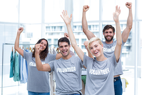 Portrait of happy volunteers friends raising arms