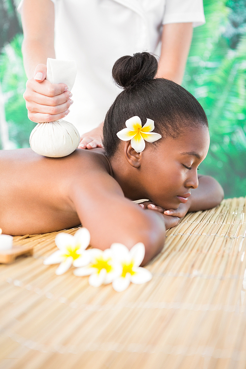 Pretty woman enjoying a herbal compress massage at the health spa