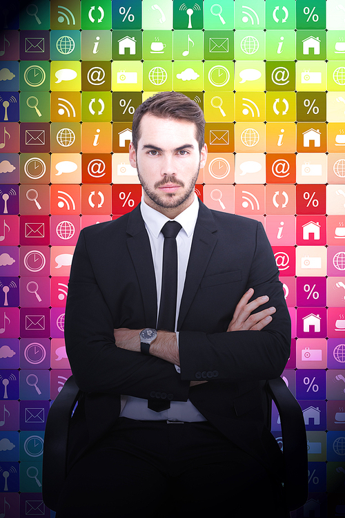 Serious businessman sitting with arms crossed against app wall