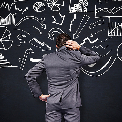 Thinking businessman scratching head against blackboard