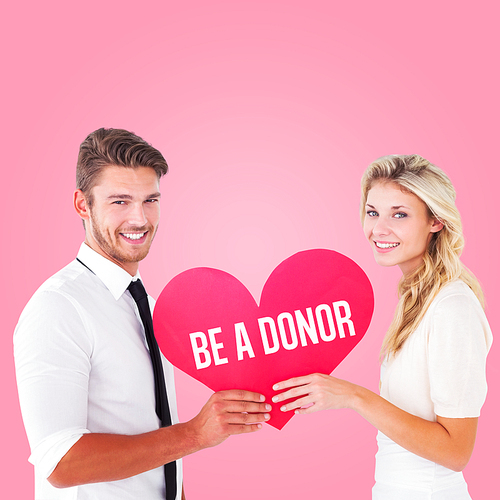 Attractive young couple holding red heart against pink